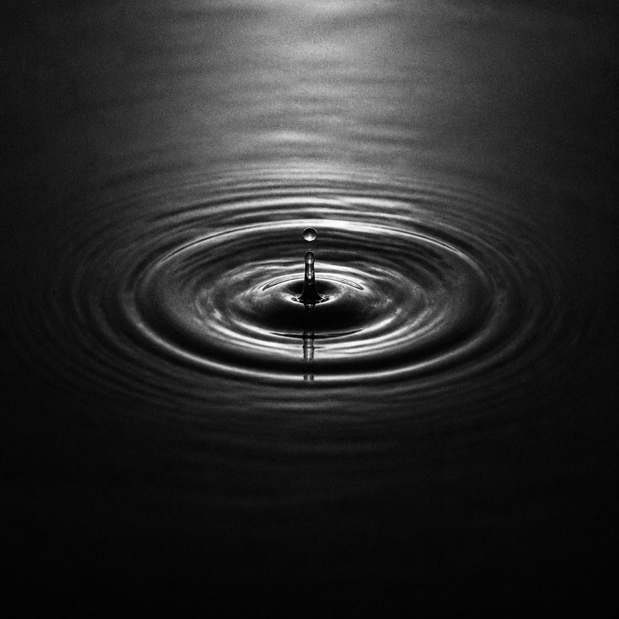 Goccia d'acqua che genera cerchi concentrici, fotografia in bianco e nero